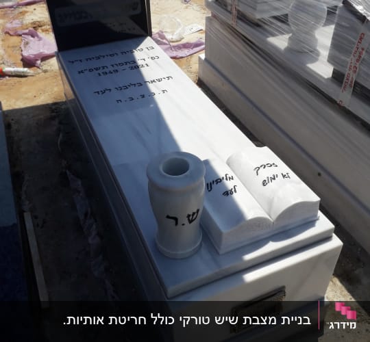 מצבה עם כיתוב בעברית, אגרטל וספרים מעוצבים